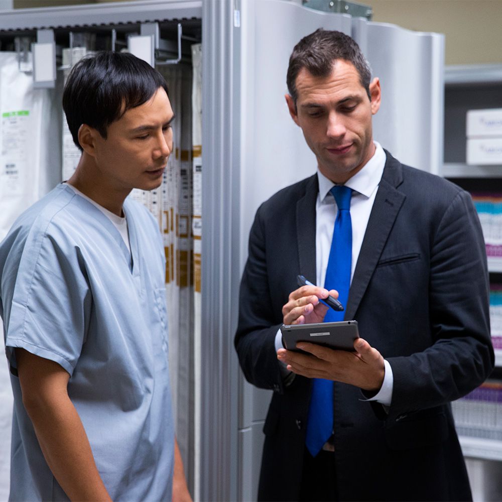 sales rep with tablet and scanner pen in supply room with medical profesional