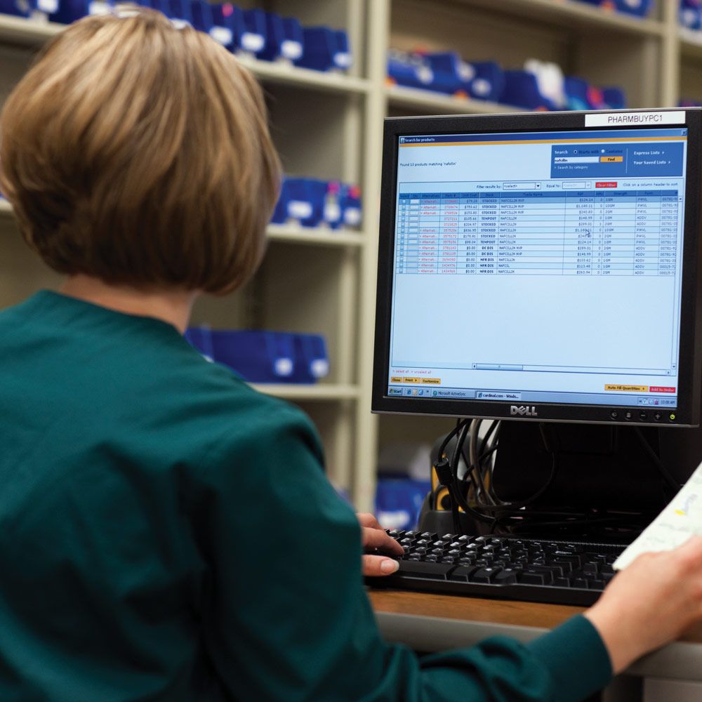 nurse in hospital pharmacy supply room looking at monitor