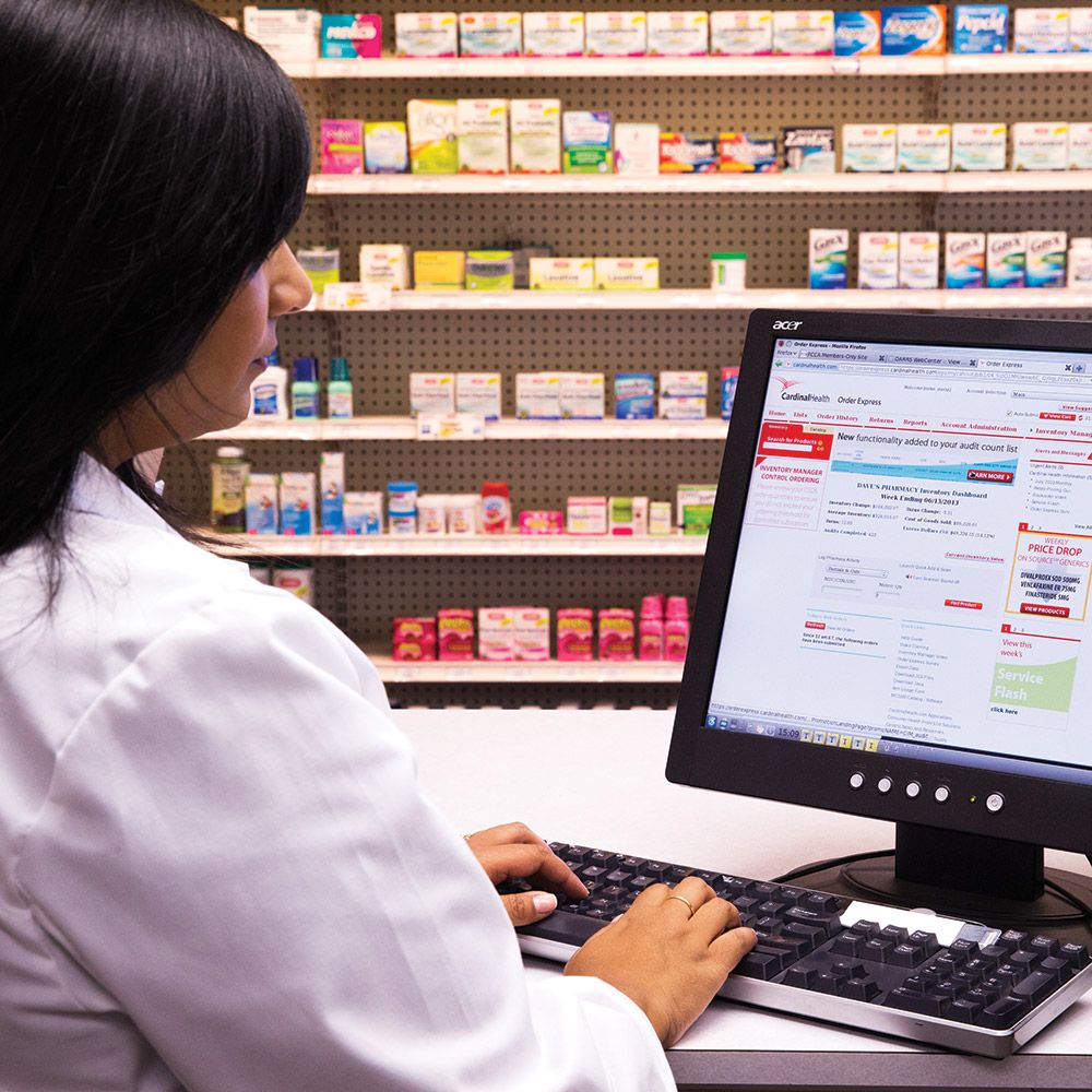 pharmacist using Order Express application on computer, in front of shelves