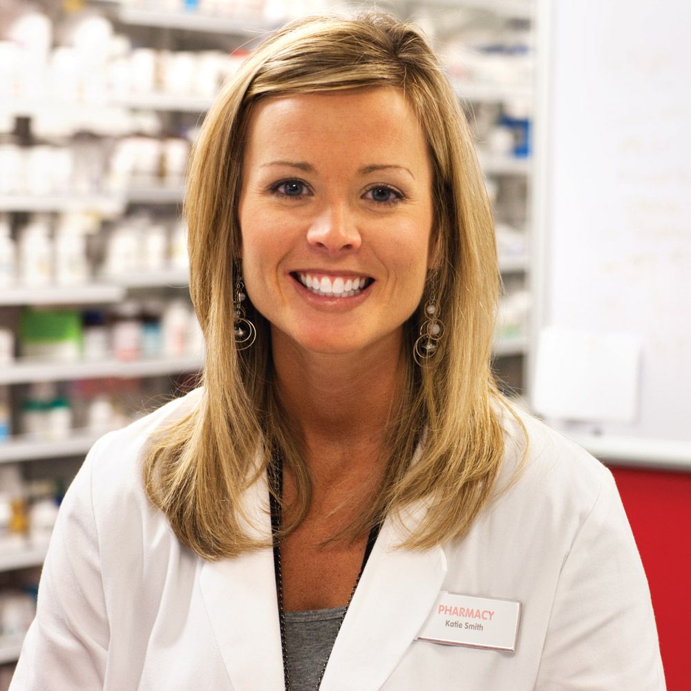 pharmacist in front of shelves, smiling