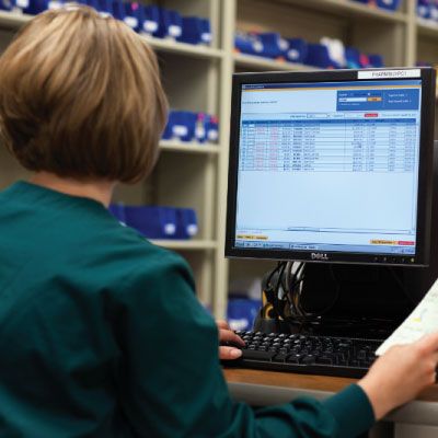 medical professional in front of computer in stock room