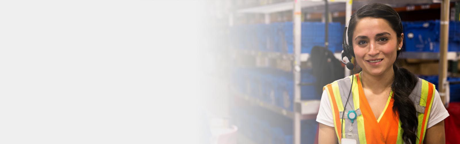 Warehouse worker wearing an orange safety vest and a headset.
