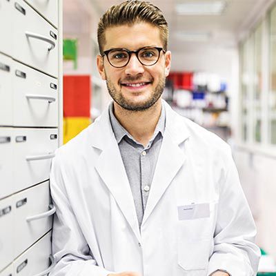 Physician with glasses leaning against a wall.