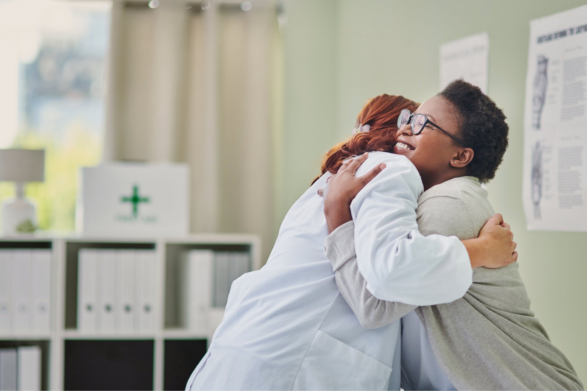 Oncologist and patient embracing during conversation about cancer treatment plan.