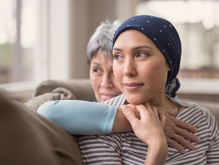 Woman with headscarf being hugged by older woman.