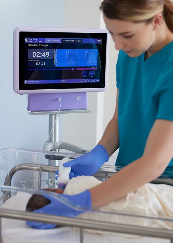 Nurse performing NTrainer Therapy on an infant in their bassinet.