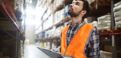 Distribution worker in orange vest looking at inventory.