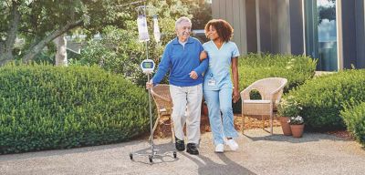 Nurse and patient with nutritional delivery device walking.