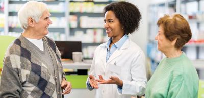 Female pharmacist consulting with elderly customers