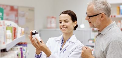 Female pharmacist showing male customer pill bottle