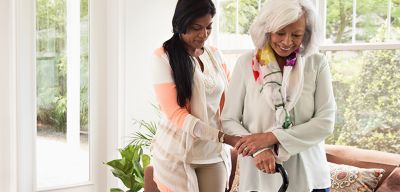Home healthcare provider helping an elderly patient with her cane.