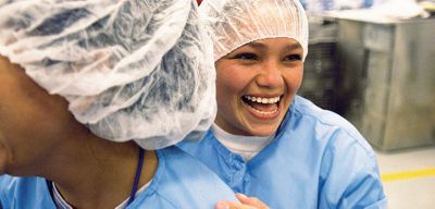 Two manufacturing employees laughing.