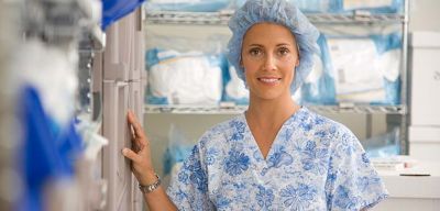 Medical professional in scrubs and a bouffant cap standing in front of Presource kitting supplies.