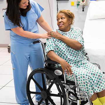 Nurse pushing a patient in a wheel chair.