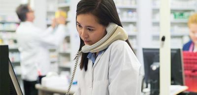 pharmacy professional on phone at computer.