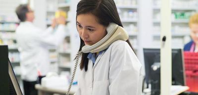 pharmacy professional on phone at computer.