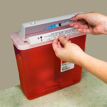 Disposing of a needle into a sharps container.